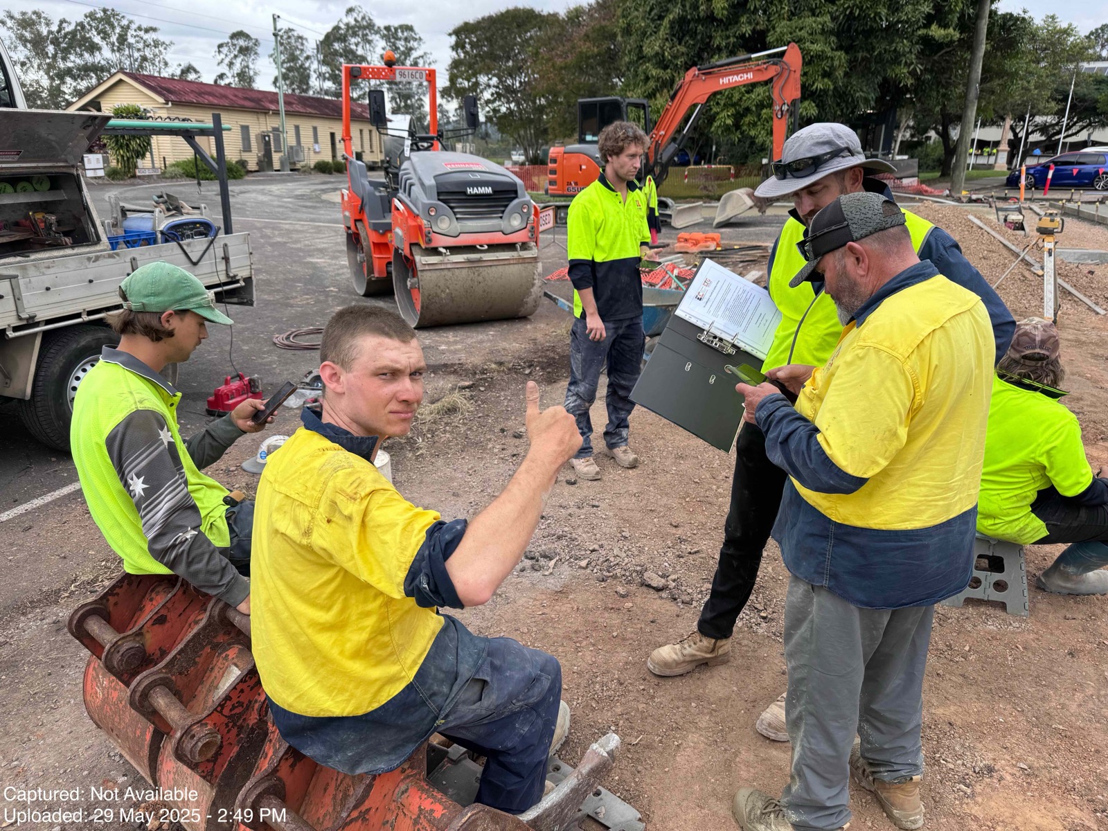Construction crew on site with an XGRIDS scanner and excavator behind